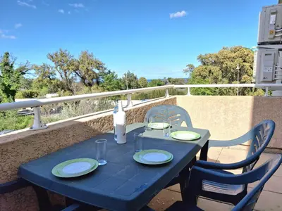 a blue table with two chairs and a bottle of wine at Villas MELODY - Appartement climatisé 4/6 pers in Santa-Maria-Poggio