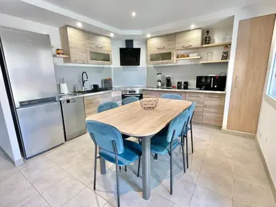 a kitchen with a wooden table and blue chairs at Appartement avec piscine 8 personnes in Porto-Vecchio