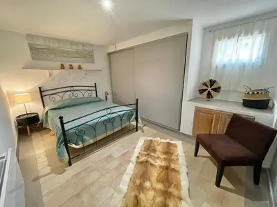 a bedroom with a bed and a chair and a table at Appartement avec piscine 8 personnes in Porto-Vecchio