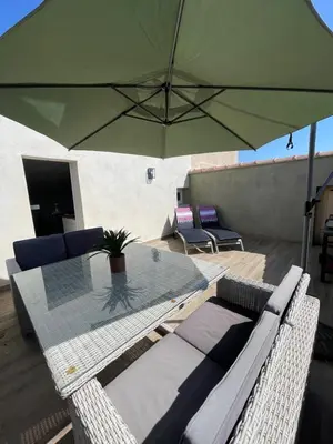 a table and chairs with a green umbrella at Appartement Terrasse in Porto-Vecchio