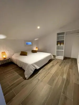 a bedroom with a large bed and a wooden floor at Appartement Terrasse in Porto-Vecchio