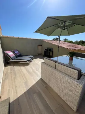 a patio with a couch and an umbrella and a table at Appartement Terrasse in Porto-Vecchio