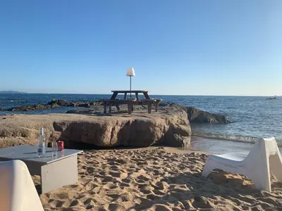 a table and chairs on a beach with the ocean at Coin de paradis aux Sanguinaires in Ajaccio