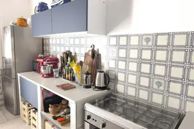 a kitchen with a white counter and a tiled wall at Ecological house with solar electricity in Ajaccio