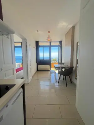 a kitchen and dining room with a view of the ocean at L'AZUR des calanques - T2 avec Piscine Chauffée & Vue Mer Exceptionnelle- Parking & Wifi in Ajaccio