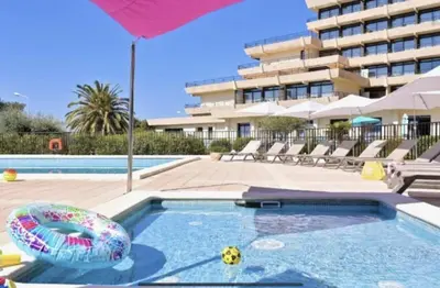 a swimming pool with an umbrella and an inflatable pool at L'AZUR des calanques - T2 avec Piscine Chauffée & Vue Mer Exceptionnelle- Parking & Wifi in Ajaccio