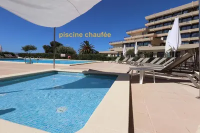 a swimming pool with chairs and a building at L'AZUR des calanques - T2 avec Piscine Chauffée & Vue Mer Exceptionnelle- Parking & Wifi in Ajaccio