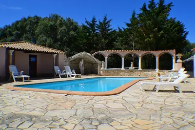 a swimming pool in a yard with chairs and a house at Domaine De Foresta in Bonifacio