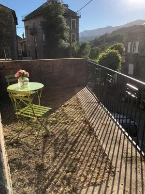 a table with a vase of flowers on a balcony at Entre montagne et mer in Bastelica