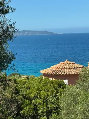 a tile roofed building with the ocean in the background at Altagna in Olmeto