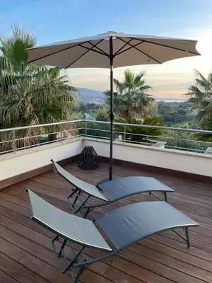 a patio with two chairs and an umbrella on a deck at Le Deck Porticcio in Grosseto-Prugna