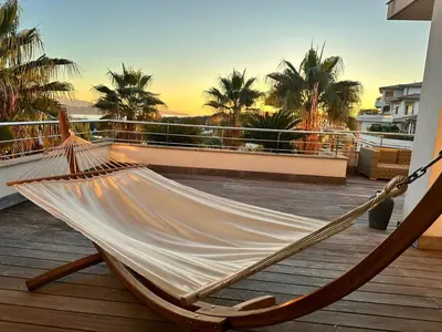 a hammock on top of a balcony with palm trees at Le Deck Porticcio in Grosseto-Prugna