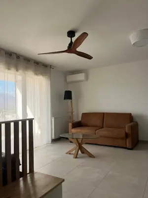 a living room with a couch and a ceiling fan at Cœur Ajaccio calme plage nature in Ajaccio