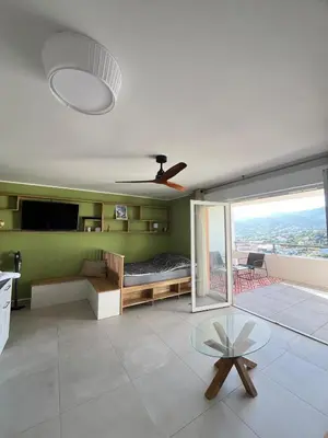 a living room with a bed and a ceiling fan at Cœur Ajaccio calme plage nature in Ajaccio