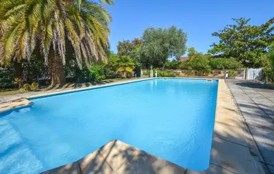 a large blue swimming pool in a yard with palm trees at Villa Plage À Pieds in Moriani Plage
