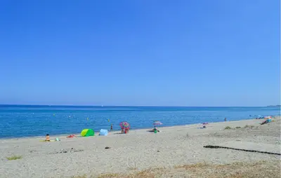 a group of people on a beach with the ocean at Villa Plage À Pieds in Moriani Plage