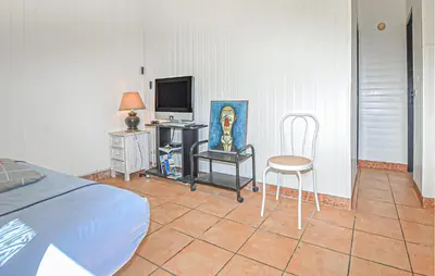 a bedroom with a bed and a tv and a chair at Villa Plage À Pieds in Moriani Plage