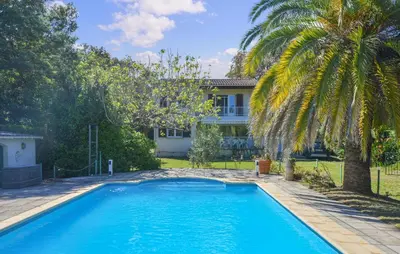 a swimming pool in front of a house with a palm tree at Villa Plage À Pieds in Moriani Plage
