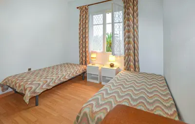 a bedroom with two beds and a window with curtains at Villa Plage À Pieds in Moriani Plage
