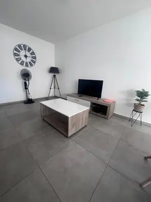 a living room with a table and a clock on the wall at Appartement T3 , 6 couchages in Ajaccio