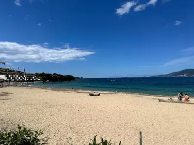 a beach with people sitting on the sand and the ocean at Les Oiseaux de Porticcio in Grosseto-Prugna