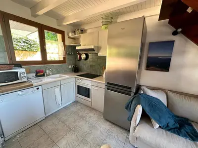 a kitchen with a stainless steel refrigerator and a couch at Les Oiseaux de Porticcio in Grosseto-Prugna