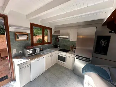 a kitchen with white cabinets and a refrigerator at Les Oiseaux de Porticcio in Grosseto-Prugna