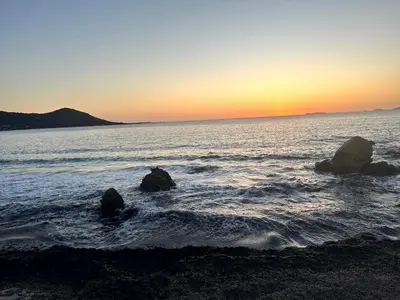 a beach with rocks in the water at sunset at Les Oiseaux de Porticcio in Grosseto-Prugna