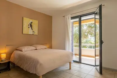 a bedroom with a bed and a large window at Cozy Apartment with Pool in Olmeto