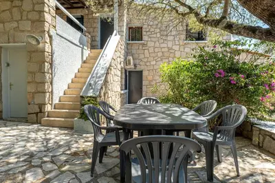 a table and chairs in front of a building at Cozy Apartment with Pool in Olmeto
