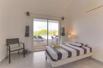 a bedroom with a bed and a chair and a patio at Padulaccia by Pinarello Villa Services in Pinarellu