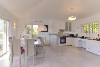 a kitchen with white cabinets and a table and chairs at Padulaccia by Pinarello Villa Services in Pinarellu