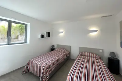 two beds in a room with white walls at Villa Alta Vista in Porto-Vecchio