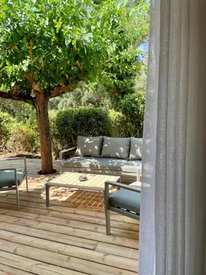 a couch sitting on a wooden deck with a tree at Camping Arutoli in Porto-Vecchio