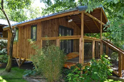 a wooden cabin in the woods with a porch at Camping Arutoli in Porto-Vecchio