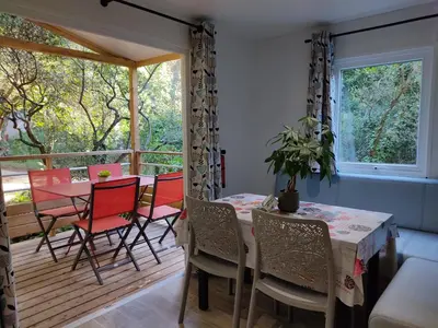 a dining room with a table and chairs on a deck at Camping Arutoli in Porto-Vecchio