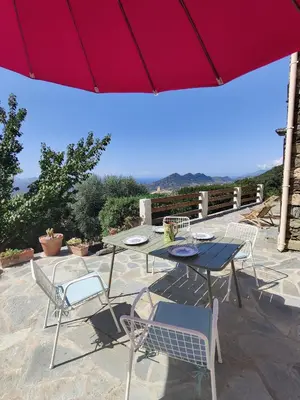 a patio with a table and chairs and an umbrella at Casa Orsu vue panoramique in Poggio-dʼOletta