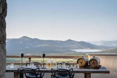 a wooden table with chairs and wine barrels on a balcony at Ecodomaine & Distillerie U Viaghju in Muro