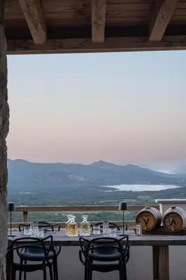 a table with chairs and a view of the mountains at Ecodomaine & Distillerie U Viaghju in Muro