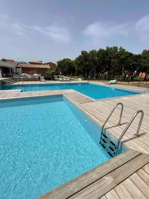 a large swimming pool with a wooden deck at T2 Saint Cyprien proche de la mer in Lecci