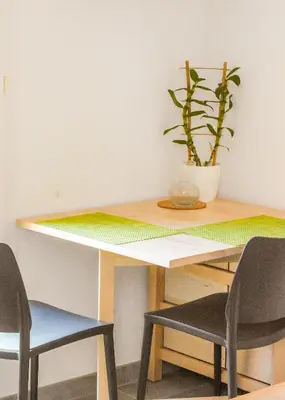 a wooden table with two chairs and a potted plant at T2 Saint Cyprien proche de la mer in Lecci