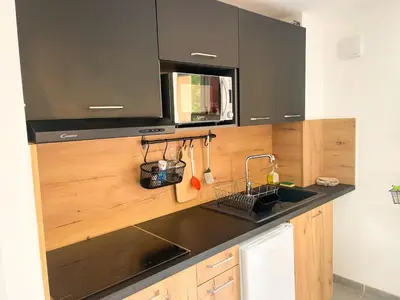 a kitchen with black cabinets and a sink at T2 Saint Cyprien proche de la mer in Lecci
