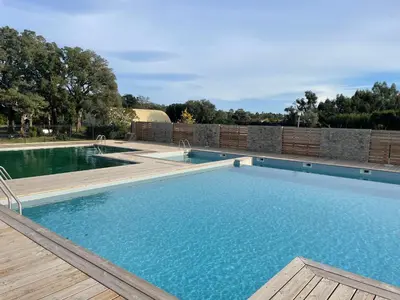 a large swimming pool with a wooden deck at T2 Saint Cyprien proche de la mer in Lecci