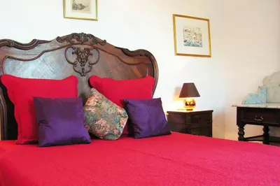 a bedroom with a red bed with purple pillows at Maison de caractère spacieuse et confortable, grand jardin , superbes vues in Castello-di-Rostino