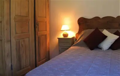 a bedroom with a bed and a lamp on a night stand at Maison de caractère spacieuse et confortable, grand jardin , superbes vues in Castello-di-Rostino