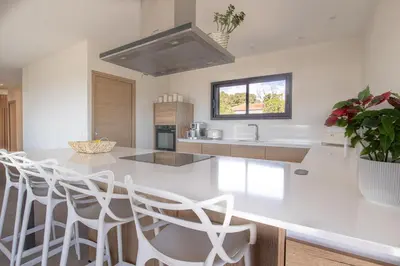 a kitchen with a white counter top and white chairs at Villa MARE E MACCHIA in Lecci