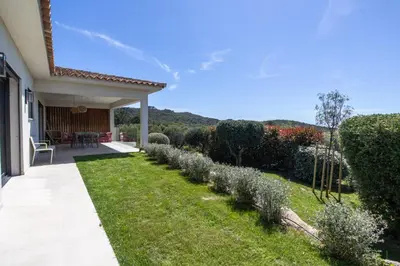 a backyard with a row of bushes and a house at Villa MARE E MACCHIA in Lecci