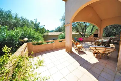 a patio with an archway and a table and chairs at Maison Famiglia Sérénité et nature in Porto-Vecchio