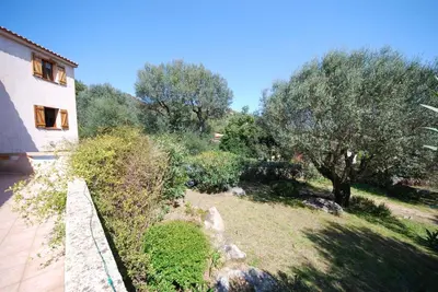 a garden with trees and a fence next to a building at Maison Famiglia Sérénité et nature in Porto-Vecchio