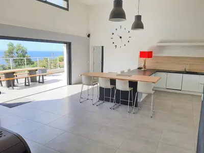 a kitchen with a table and chairs and a view of the ocean at Superbe villa moderne sur Capo di Muro in Coti-Chiavari